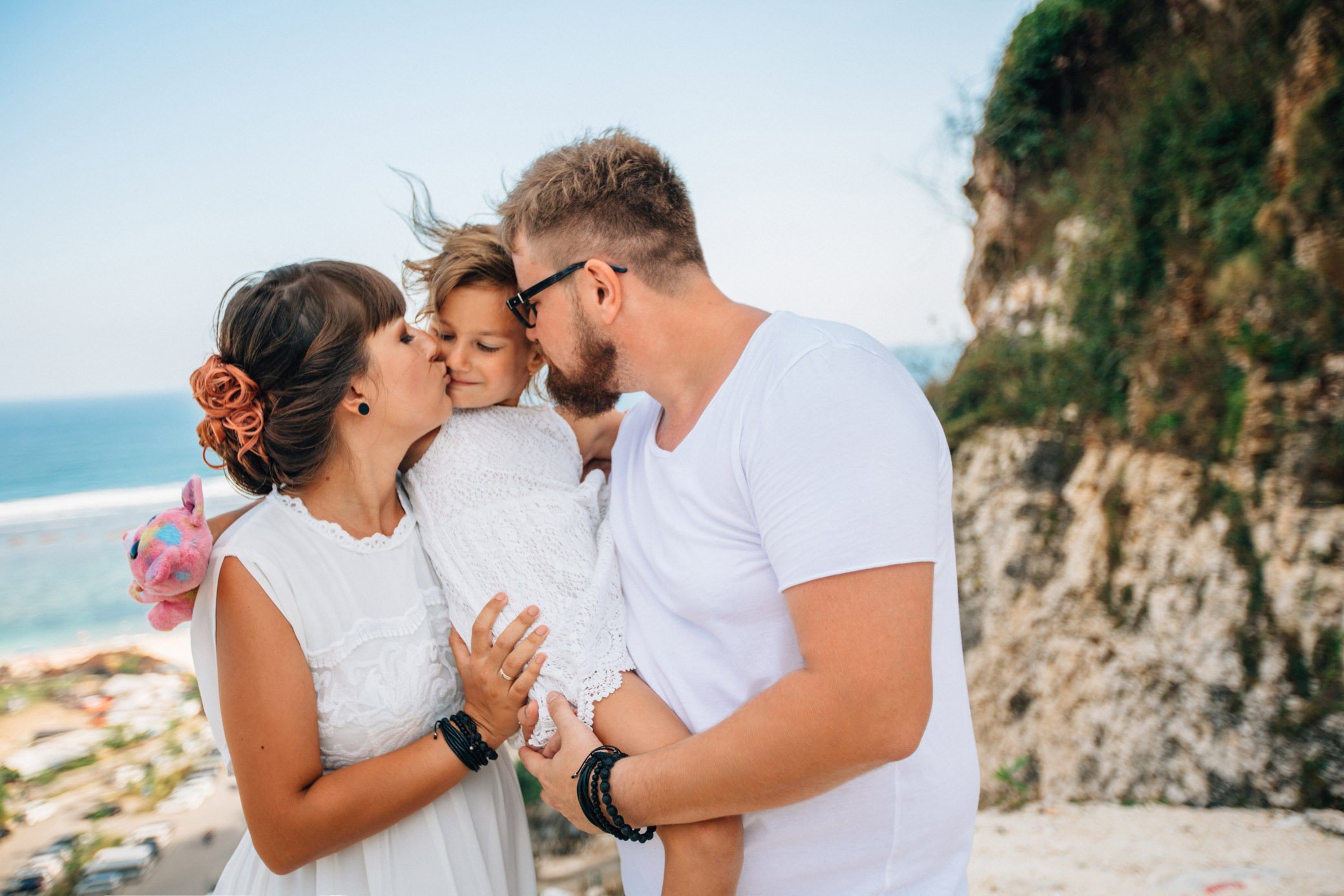 
Dad holds his daughter in his arms, and my mother kisses her cheek lovingly. A man in glasses and a white T-shirt, a woman and a little girl in a white dress.